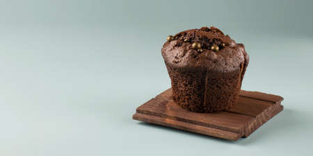 Delicious chocolate cupcake on a wooden board on a blue background. Festive concept. Minimalism....
