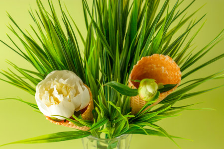 Close-up Ice cream cone for ice cream with white peony flower on green background. Festive creative...