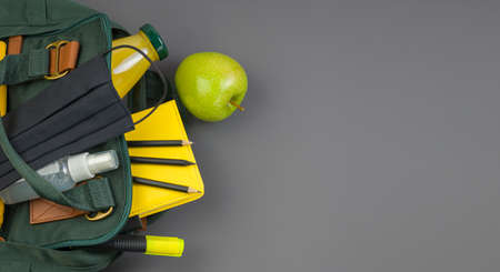 Bright school and office supplies, medical face mask on a dark background. Back to school concept. Social distance, learning and home education. Stay safe. Copy space.の写真素材