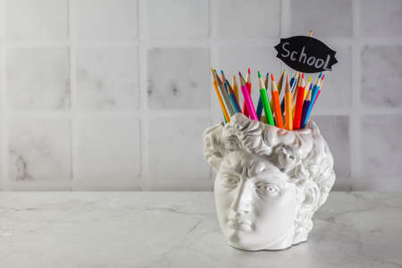 Fashionable concept. David's head plaster stand for office, creative and school supplies on a light...