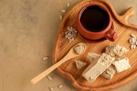 Eastern sweetness. Halva sunflower on a wooden board and background with textiles. Natural vegan...