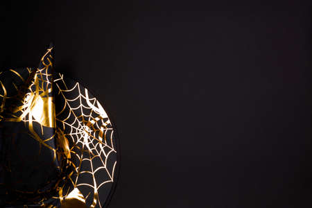 Halloween holiday. Serving on a dark table with a black pointed conical witch hat and black cutlery. Flat lay, top view trendy holiday concept. Copy spaceの写真素材