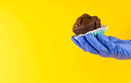 Birthday holiday. Chocolate muffin with candles in hand, protected by a glove. Safe food concept....