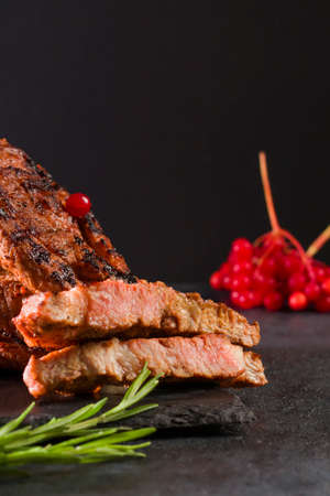 Grilled cuts of meat, hot steak on a slate stone table. Juicy food for drinks. Side view. Vertical positionの写真素材