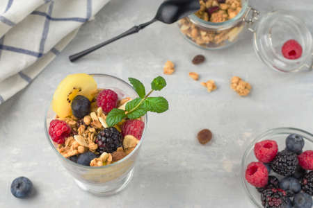 A glass of muesli, berries and yoghurt parfait on the table. Healthy breakfast. Granola with...