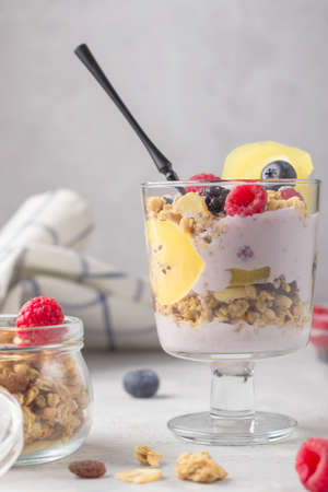 Granola with raspberries, blueberries and golden kiwi. Glass of muesli, berries and yogurt parfait...