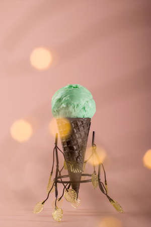 Delicious summer dessert. Homemade mint ice cream in a waffle cone on a pink background. natural healthy food. bokeh effect. vertical positionの写真素材