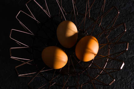 Natural brown eggs in a metal basket on a dark background. hard shadows. top view. Baking ingredientsの写真素材