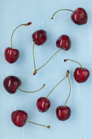Red ripe cherries on a blue background in the water. view from above. flat layout. texture, patternの写真素材