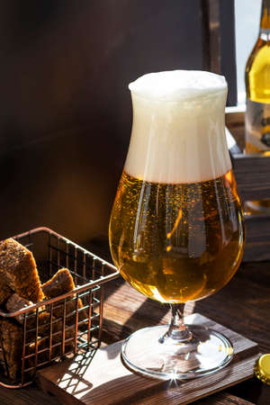 A glass of light tasty beer on a wooden pub table. organic products