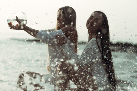 Two pretty girls sitting on beachの写真素材