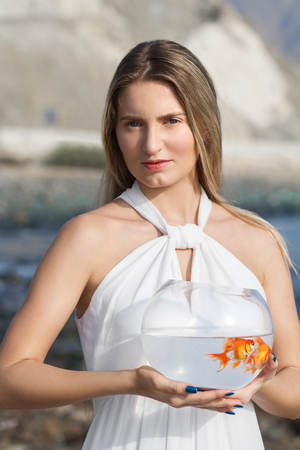 woman holding golden fish in her handsの写真素材