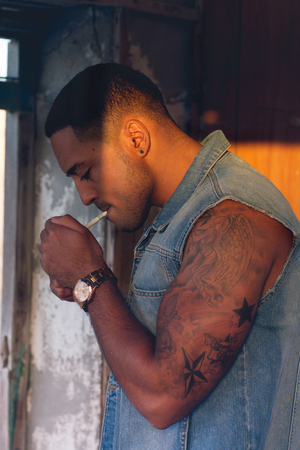 Young sexy man with tattoo outdoor, smokingの写真素材