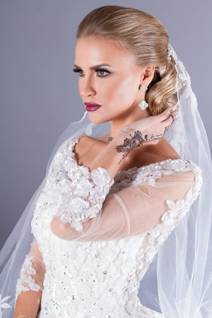 elegant blond bride with strong make up and wedding hairstyle on blue backgroundの写真素材