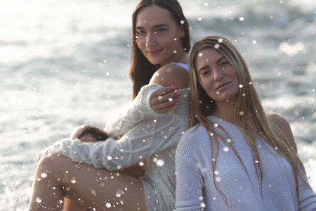 Two pretty girls sitting on beachの写真素材