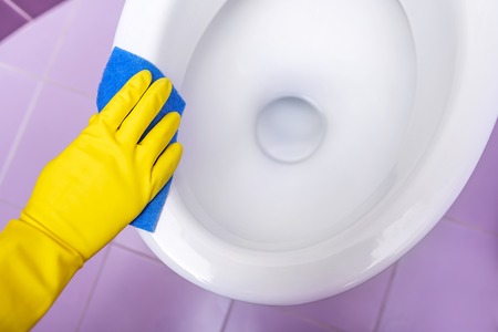Hands in yellow gloves washing a toilet bowl.の写真素材