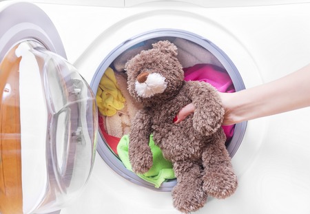 Teddy bear in a washing machine. Preparing the wash cycle.の写真素材