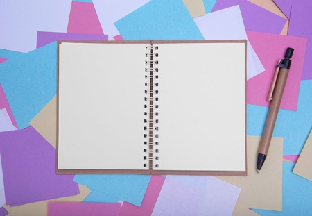 Open notebook with a pen on the background of colored stickers.の写真素材