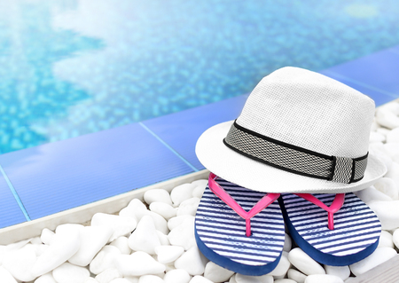 Flip-flops and hat at the pool on the white gravel.の写真素材