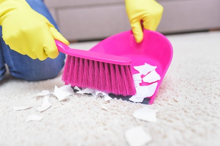 Female hands in yellow gloves sweeping a carpet brush.の写真素材