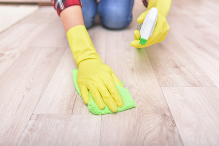 Female hands in yellow gloves wipe the floor rag.の写真素材