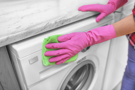 Female hands in gloves washing washing machine. Close-up.の写真素材