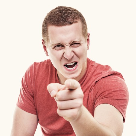 Young man on white background menacingly points a finger. Toned photo.