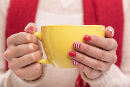 Women's hands holding a cup of drink. Winter clothes.の写真素材
