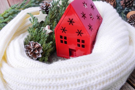 Red house, wrapped in a scarf on a background of greenery and cones.の写真素材