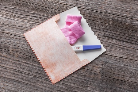 Pregnancy test in the envelope and baby socks.の写真素材