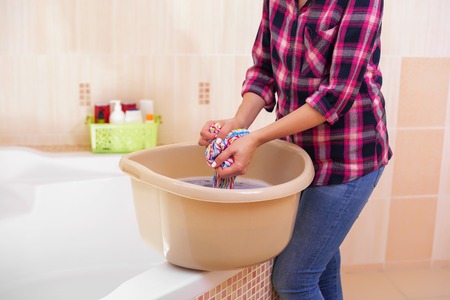 Womens hands wash clothes in the basin.の写真素材