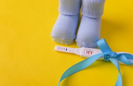 Baby socks and a pregnancy test on a yellow background.の写真素材