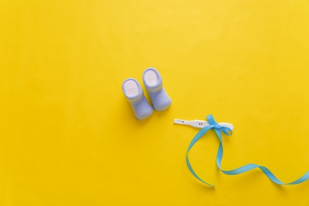 Baby socks and a pregnancy test on a yellow background.
