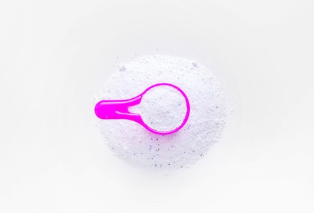 Washing powder in a measuring cup on a white table.の写真素材