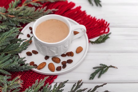 Cup of cappuccino on the background of a warm scarf and fir branches.の写真素材