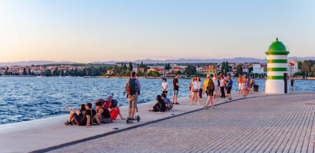 Adriatic Sea Embankment with a lighthouse and tourists in the summer in Zadar, Croatia.のeditorial素材