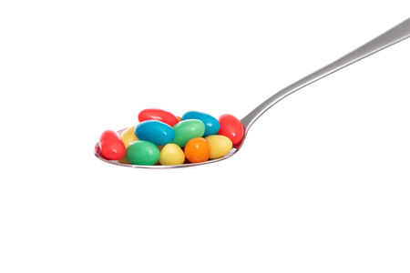 Multi-colored candies in a spoon on white background.の写真素材