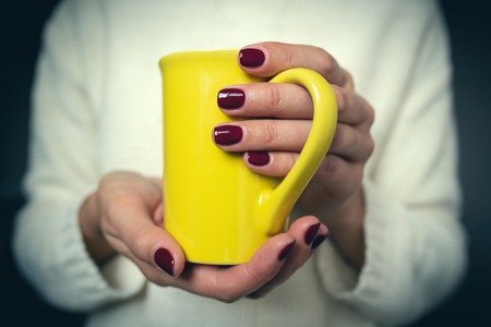 Young woman holds a cup with a hot drink in her hands.の写真素材