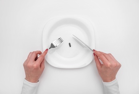 Tablet on a plate. Female hands and drugs on a plate as a concept.