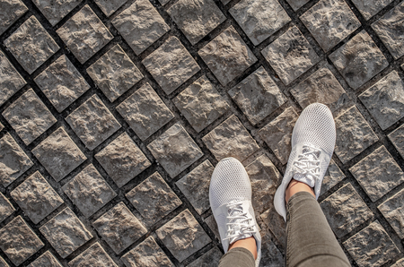Womens legs in white sneakers on the pavement.の写真素材