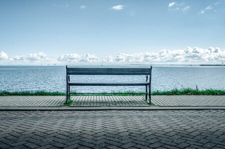Bench on the shore of a lake or a sea.