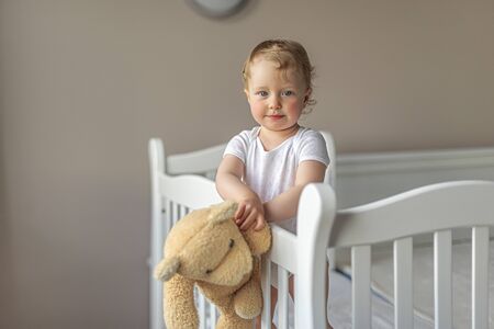 Cheerful little girl playing with a teddy bear in a good mood.の写真素材