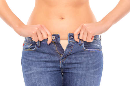 Losing weight. Slender girl in big jeans on a white background.