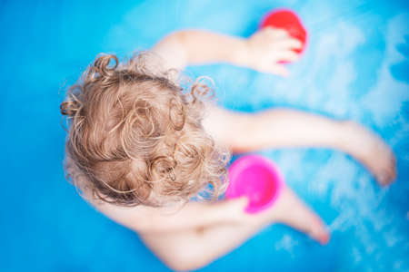 Child girl bathes in a bathtub or pool with toys.の写真素材