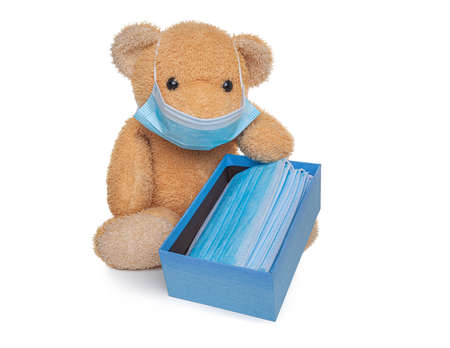 Teddy bear soft toy holds a box with medical masks.の写真素材