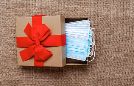 Gift box with medical masks on a burlap background.
