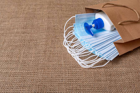 Medical masks and antiseptic on a burlap background.