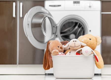 Childrens toys in a basket on the background of a washing machine.の写真素材