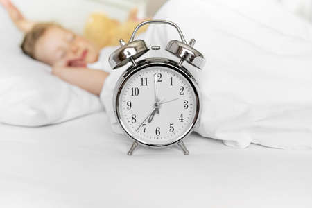 Alarm clock on the background of a sleeping child.