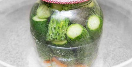 A jar of cucumbers is cooked in a pot of boiling water.の写真素材